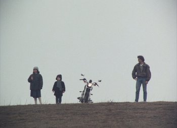 Movie still from “Landscape in the Mist” (1988), directed by Theodoros Angelopoulos – A group of people standing on top of a grass covered hill; Wide shot, Low angle