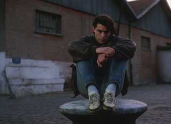 Movie still from “Landscape in the Mist” (1988), directed by Theodoros Angelopoulos – A man sitting on top of a stone bench; Medium shot, High angle