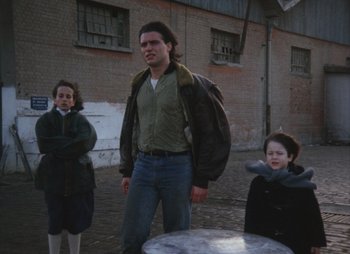 Movie still from “Landscape in the Mist” (1988), directed by Theodoros Angelopoulos – A man standing next to two young girls; Medium shot, Low angle