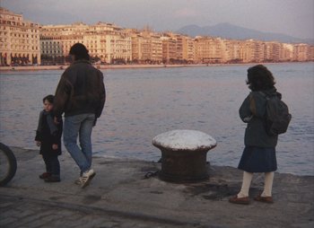 Movie still from “Landscape in the Mist” (1988), directed by Theodoros Angelopoulos – A group of people standing next to a body of water; Wide shot, High angle