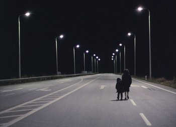 Movie still from “Landscape in the Mist” (1988), directed by Theodoros Angelopoulos – A woman and a little girl walking down a street at night; Extreme Wide shot, High angle
