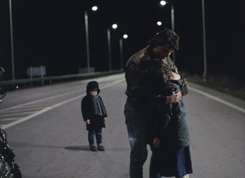 Movie still from “Landscape in the Mist” (1988), directed by Theodoros Angelopoulos – A man and a woman and a child on a street; Wide shot, Over the shoulder angle