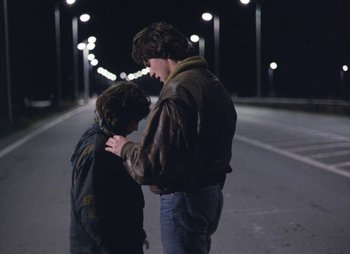 Movie still from “Landscape in the Mist” (1988), directed by Theodoros Angelopoulos – A man standing next to a young boy on a street; Medium shot, Over the shoulder angle