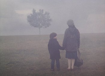 Movie still from “Landscape in the Mist” (1988), directed by Theodoros Angelopoulos – A woman and a child standing in a field in the fog; Wide shot, High angle