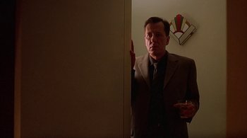 Movie still from “Lantana” (2001), directed by Ray Lawrence – A man wearing a suit and tie standing next to a wall; Medium shot, Low angle
