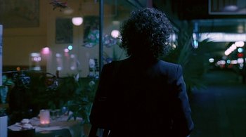 Movie still from “Lantana” (2001), directed by Ray Lawrence – A person with curly hair standing in front of a window at night; Medium shot, Over the shoulder angle