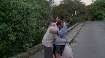 Movie still from “Lantana” (2001), directed by Ray Lawrence – A group of men hugging on the side of the road; Wide shot, High angle