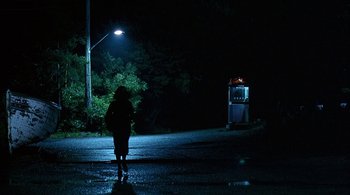 Movie still from “Lantana” (2001), directed by Ray Lawrence – A person standing on the side of a road at night; Extreme Wide shot, Low angle