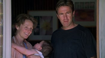 Movie still from “Lantana” (2001), directed by Ray Lawrence – A man and a woman holding a baby in a room; Close Up shot, Low angle