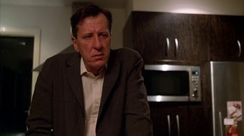 Movie still from “Lantana” (2001), directed by Ray Lawrence – A man wearing a suit and tie in a kitchen; Close Up shot, Low angle