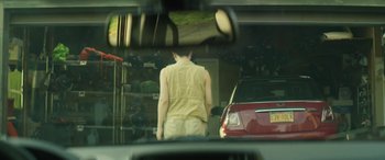 Movie still from “Lapsis” (2020), directed by Noah Hutton – A man standing in front of a car in a mirror; Medium shot, Over the shoulder angle