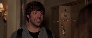 Movie still from “We're the Millers” (2013), directed by Rawson Marshall Thurber – A person smiling near a door; Close Up shot, Over the shoulder angle