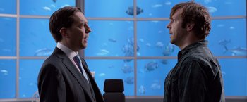 Movie still from “We're the Millers” (2013), directed by Rawson Marshall Thurber – Two men in suits talking in front of an aquarium window; Medium shot, Over the shoulder angle