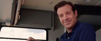 Movie still from “We're the Millers” (2013), directed by Rawson Marshall Thurber – A man smiling while holding a steering wheel of a vehicle; Close Up shot, Over the shoulder angle