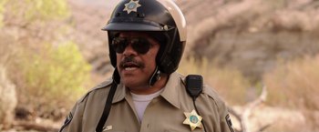 Movie still from “We're the Millers” (2013), directed by Rawson Marshall Thurber – A man in a police uniform with a badge on his chest; Close Up shot, Over the shoulder angle