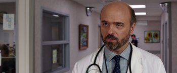 Movie still from “We're the Millers” (2013), directed by Rawson Marshall Thurber – A man with a stethoscope in a room; Close Up shot, Over the shoulder angle