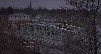 Movie still from “Lars and the Real Girl” (2007), directed by Craig Gillespie – A metal bridge over a body of water near trees; Extreme Wide shot, High angle
