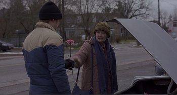 Movie still from “Lars and the Real Girl” (2007), directed by Craig Gillespie – An older woman holding a pink flower in her left hand; Medium shot, Over the shoulder angle
