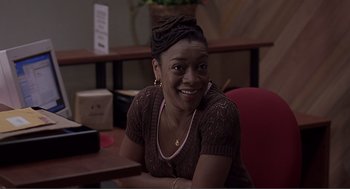 Movie still from “Lars and the Real Girl” (2007), directed by Craig Gillespie – A woman sitting at a table smiling for the camera; Medium shot, High angle
