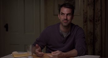 Movie still from “Lars and the Real Girl” (2007), directed by Craig Gillespie – A man sitting at a table with a glass of water in front of him; Medium shot, Over the shoulder angle
