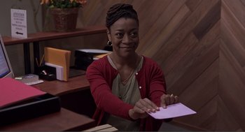 Movie still from “Lars and the Real Girl” (2007), directed by Craig Gillespie – A woman sitting at a desk holding a piece of paper; Medium shot, High angle
