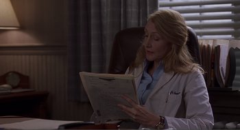 Movie still from “Lars and the Real Girl” (2007), directed by Craig Gillespie – A woman sitting at a table reading a paper; Medium shot, Over the shoulder angle