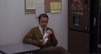 Movie still from “Lars and the Real Girl” (2007), directed by Craig Gillespie – A man sitting in front of a refrigerator holding a bag of chips; Medium shot, High angle