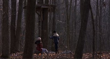 Movie still from “Lars and the Real Girl” (2007), directed by Craig Gillespie – Two people sitting in the woods near a tree; Wide shot, Low angle