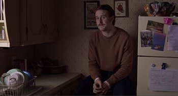 Movie still from “Lars and the Real Girl” (2007), directed by Craig Gillespie – A man sitting on a counter in a kitchen; Medium shot, Over the shoulder angle