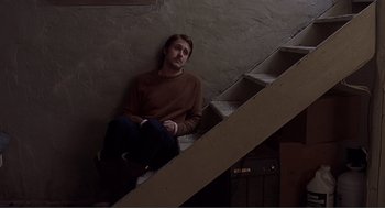 Movie still from “Lars and the Real Girl” (2007), directed by Craig Gillespie – A man sitting on the bottom of a stair case; Wide shot, Low angle