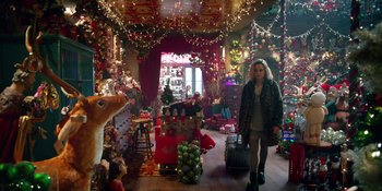 Movie still from “Last Christmas” (2019), directed by Paul Feig – A woman walks through a room decorated for christmas; Wide shot, High angle
