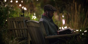 Movie still from “Last Christmas” (2019), directed by Paul Feig – A man sitting on top of a wooden park bench; Medium shot, High angle