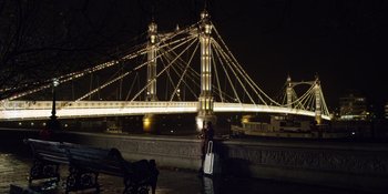 Movie still from “Last Christmas” (2019), directed by Paul Feig – A person standing on a bench in front of a bridge at night; Extreme Wide shot, High angle