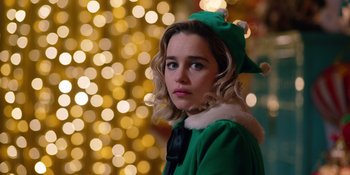 Movie still from “Last Christmas” (2019), directed by Paul Feig – A woman dressed as a christmas elf in front of a christmas tree; Close Up shot, Over the shoulder angle