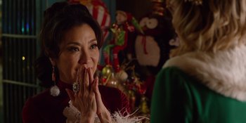 Movie still from “Last Christmas” (2019), directed by Paul Feig – A woman in a red dress is holding her hands to her mouth; Close Up shot, Over the shoulder angle