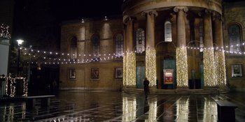 Movie still from “Last Christmas” (2019), directed by Paul Feig – A person standing in front of a building at night; Extreme Wide shot, High angle
