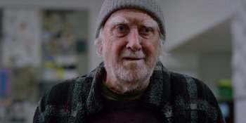 Movie still from “Last Christmas” (2019), directed by Paul Feig – An older man wearing a hat and a sweater; Close Up shot, Over the shoulder angle