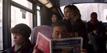 Movie still from “Last Christmas” (2019), directed by Paul Feig – A man reading a newspaper while sitting on a train; Medium shot, Over the shoulder angle