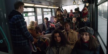Movie still from “Last Christmas” (2019), directed by Paul Feig – A group of people sitting on a bus reading newspapers; Wide shot, High angle