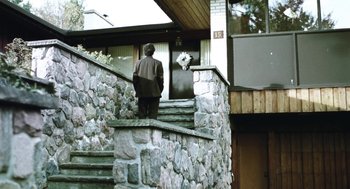 Movie still from “Last Night” (1998), directed by Don McKellar – A man walking down the steps of a stone house; Wide shot, Low angle