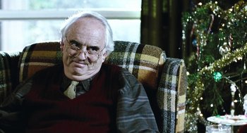Movie still from “Last Night” (1998), directed by Don McKellar – An older man sitting in a chair wearing glasses; Close Up shot, Over the shoulder angle