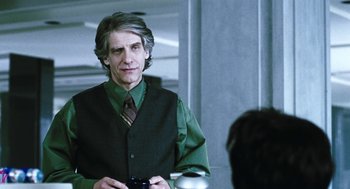 Movie still from “Last Night” (1998), directed by Don McKellar – A man in a green vest and tie holding a camera; Medium shot, Over the shoulder angle