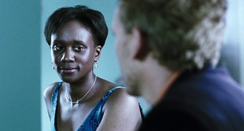 Movie still from “Last Night” (1998), directed by Don McKellar – A woman in a blue dress looking at a man in a black suit; Close Up shot, Over the shoulder angle