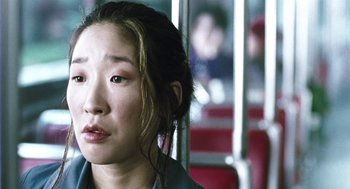 Movie still from “Last Night” (1998), directed by Don McKellar – A woman sitting on a bus looking at the camera; Close Up shot, Low angle