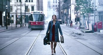 Movie still from “Last Night” (1998), directed by Don McKellar – A woman walking down the street holding a bag; Wide shot, High angle