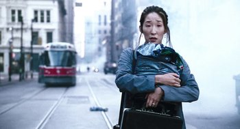 Movie still from “Last Night” (1998), directed by Don McKellar – A woman carrying a suitcase and a briefcase on a city street; Medium shot, High angle
