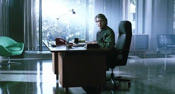 Movie still from “Last Night” (1998), directed by Don McKellar – A man sitting at a desk in front of a laptop computer; Wide shot, Low angle