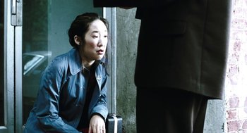 Movie still from “Last Night” (1998), directed by Don McKellar – A woman sitting on the ground with a suitcase; Medium shot, High angle