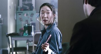 Movie still from “Last Night” (1998), directed by Don McKellar – A woman holding a candy stick in a room; Close Up shot, Over the shoulder angle