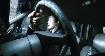 Movie still from “Last Night” (1998), directed by Don McKellar – A woman driving a car in the dark; Extreme Close Up shot, Overhead angle
